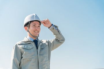 青空を背景に笑顔を見せる若手作業員